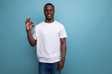 Beyaz tişörtlü koyu tenli, kendine güvenen Amerikalı bir adam..