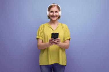 Orta yaşlı bir iş. Sarışın, kulaklıklı ve elinde akıllı telefonu olan bir kadın..