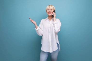 Genç, zeki, sarışın, beyaz gömlekli, kariyer sahibi bir kadın telefonda konuşuyor..