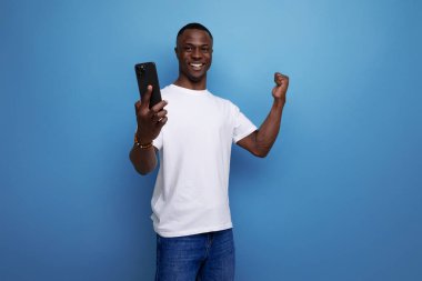 Beyaz tişörtlü pozitif Afrikalı adam internette sohbet ediyor..