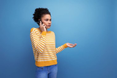 Siyah afro saçlı Latin genç bayan telefonda konuşuyor..