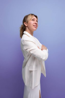 Genç, gururlu, bakımlı, sarışın, beyaz ceketli ve elbiseli patron kadın..