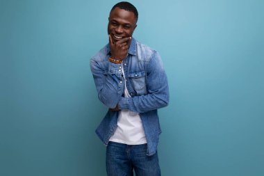 Kot ceketli genç Afrikalı adam ağzını kapatarak gülüyor..