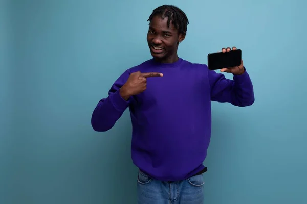 surprised joyful african young man with dreadlocks holding smartphone.