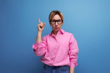 Genç, beyaz, sarışın, kariyer düşkünü, atkuyruklu, gözlüklü, pembe bluz giyen bir kadın..