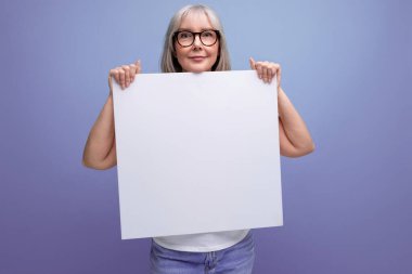 Beyaz saçlı, elinde boş çarşaf tutan, stüdyo arka planında model olan olgun bir iş kadını..