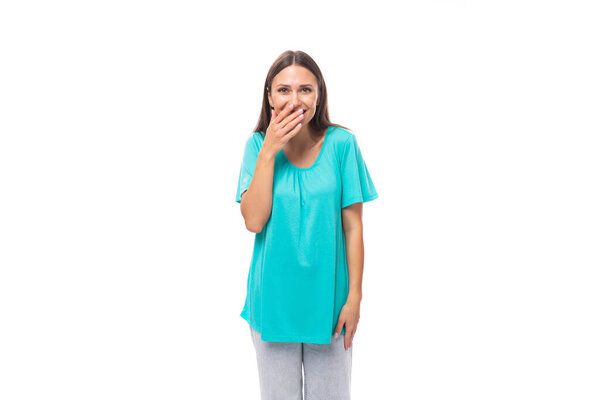 young caucasian female model with black straight hair dressed in a blue t-shirt laughs covering her mouth.