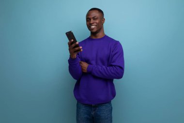 Mavi kazaklı yakışıklı Afrikalı genç telefon kullanıyor..