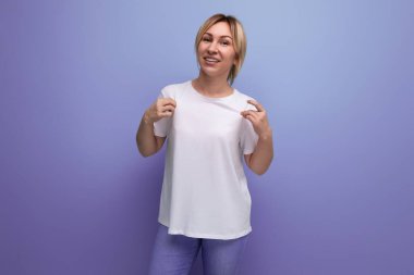 Stüdyonun arka planına fotokopi alanı olan iş bilgileri eklemek için tişört şablonu olan sarışın genç bayan..