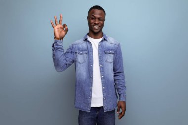 Kot ceketli yakışıklı Amerikalı genç adam mavi arka planda fotokopi aletiyle gülümsüyor..