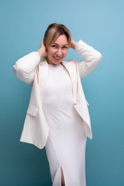 Genç neşeli pozitif sarışın zarif kadın yetişkin ceket ve elbise giyiyor..