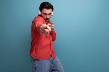 Yakışıklı, siyah saçlı genç bir adam kulaklıkla müzik dinliyor ve dans ediyor..