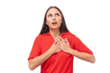 Siyah saçlı, kırmızı tişörtlü çekici genç Avrupalı kadın beyaz arka planda şaşırmış görünüyor..