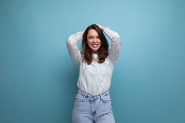 Enerjik, duygusal, esmer, çizgili gömlekli ve kot pantolonlu, stüdyo arka planında yetişkin bir kadın..