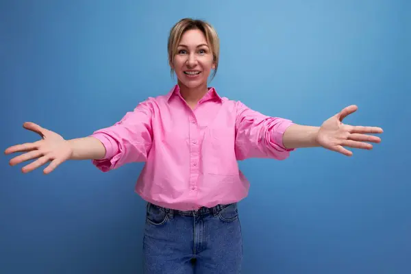 young european blond leader woman dressed in pink blouse with open arms.