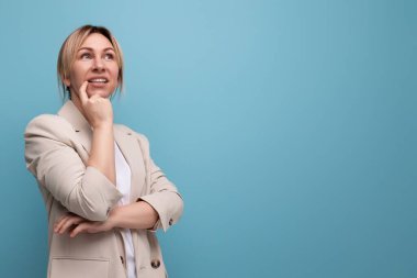 Stüdyoda gülümseyen ceketli sarışın genç iş kadını..