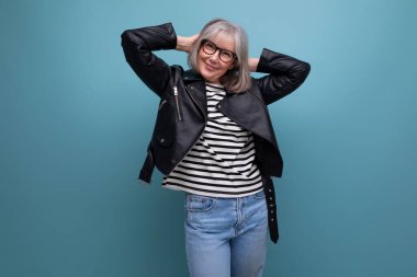 Parlak bir arka planda şık bir rockçı ceketi giymiş olgun yaşlı bir kadın..