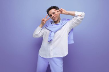 Kısa saçlı, beyaz gömlekli ve mavi pantolonlu gülümseyen genç kadın..