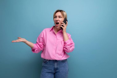 Pembe gömlekli güzel bir iş kadını stüdyo arka planında fotokopi alanı olan bir akıllı telefon kullanarak iş davalarını çözüyor..