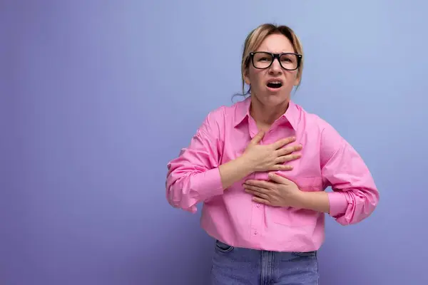 european confused surprised young blond businesswoman in pink shirt and jeans on studio background with copy space.