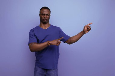 Çekici 25 'li yaşlarda, sıradan mavi tişörtlü Afrikalı bir adam parmağını kenarı işaret ediyor..