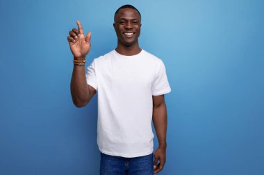 Beyaz tişörtlü yakışıklı genç bir Amerikalı elini kaldırıyor..