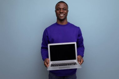 Mavi kazaklı yakışıklı Afrikalı genç reklam için dizüstü bilgisayar ekranı gösteriyor..
