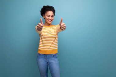 Gülümseyen esmer, kahverengi saçlı, sarı çizgili kazaklı genç kadın..