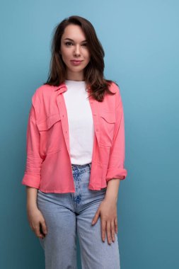 Omuzlarının altında siyah saçlı, gömlek ve kot pantolonlu, kendine güvenen esmer kadın..