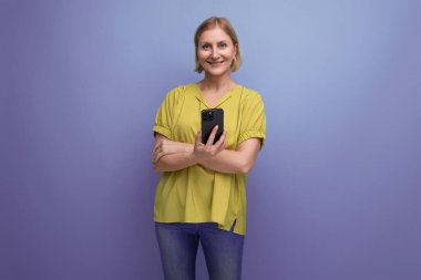 Sarışın olgun bir kadın akıllı telefon kullanarak sohbet ediyor..