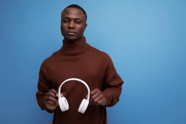 Pozitif genç Amerikalı erkek DJ arka planda fotokopi alanı ile kulaklıklarını çıkardı..