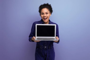 Mavi kot pantolon giymiş genç, mutlu esmer kadın dizüstü bilgisayar ekranını modelliyor..