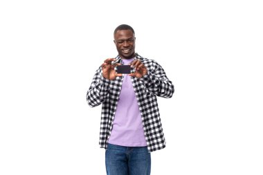 Ekose gömlekli ve kotlu çekici, koyu tenli bir adamın portresi. Elinde plastik bir kart var..