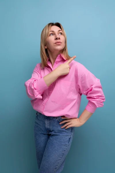 young blond european leader woman with shoulder-length hair in a pink blouse points her finger towards the advertisement.