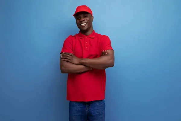handsome young courier american man wearing corporate clothing consisting of a red cap and t-shirt.