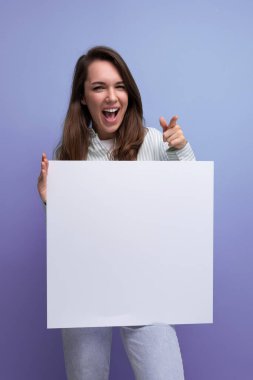 Sevimli 25 yaşındaki esmer kadın, gömlek ve kot pantolon içinde beyaz çarşaf üzerinde bir proje gösteriyor..