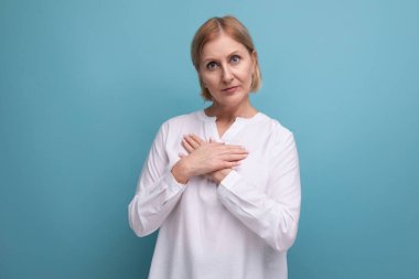 Beyaz bluzlu, ince, sarışın, orta yaşlı bir kadın..