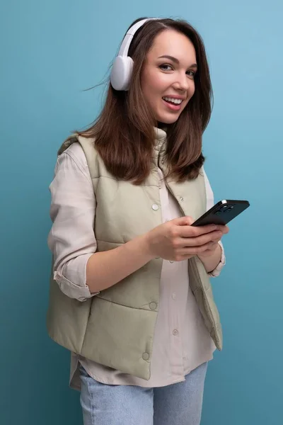 young brunette woman with headphones and a phone in her hands.