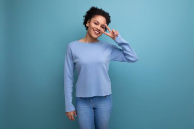 Genç, başarılı, koyu tenli, kabarık saçlı, mavi elbiseli, arka planda kopya alanı olan bir kadının yakın çekimi..