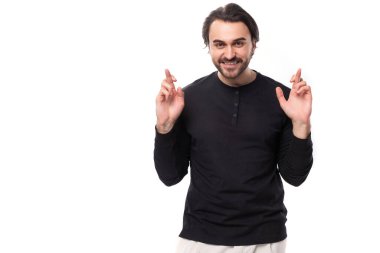 Siyah tişörtlü yakışıklı Avrupalı adam izole beyaz arka planda parmaklarını çapraz yaptı..
