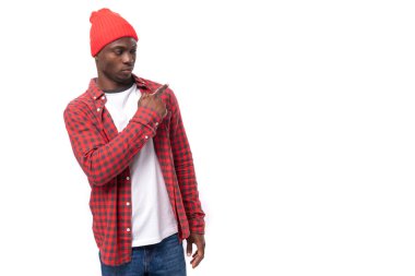 Kırmızı gömlekli ve şapkalı 30 'lu yaşlarda beyaz stüdyo arka planındaki boş duvara fotokopi çeken siyahi bir adamın portresi..