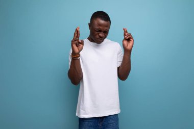 Beyaz tişörtlü, stüdyo arka planında fotokopi alanı olan düşünceli, çekici genç Amerikalı adam..