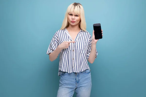 blond 25 year old female person in a striped blouse and jeans shows the smartphone screen.