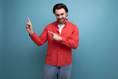 Genç Avrupalı yakışıklı adam şık saç stili ile elini yana doğru gösteriyor..