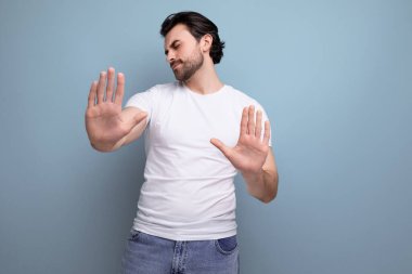 Beyaz tişörtlü, sakallı esmer adam stüdyo arka planında fotokopi alanı olan ret hareketi gösteriyor..