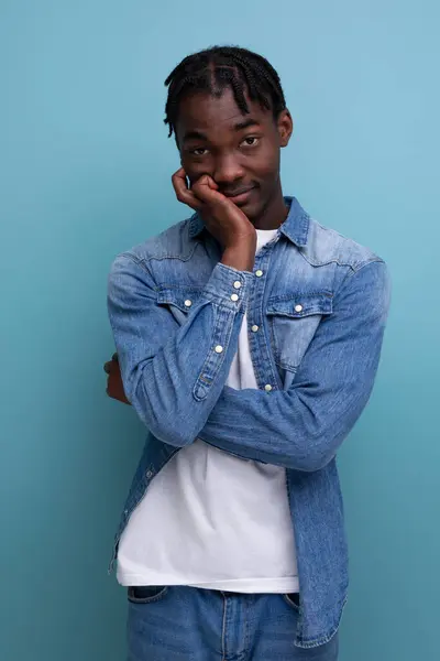 portrait of a shy young african man with dreadlocks in a denim jacket posing thoughtfully.