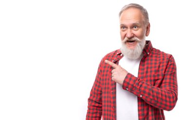 Olgun, gri saçlı, sakallı bir adam beyaz bir arka planda parmağını işaret ediyor..