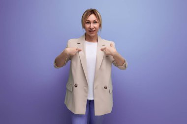 Bej ceketli sarışın iş kadını stüdyo arka planında parmağı olan bir fikri olduğunu gösteriyor..