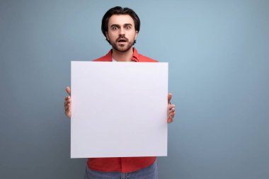 Beyaz kağıt posterli, kırmızı tişörtlü, çekici, pozitif 30 'lu yaşlarda bir adam..