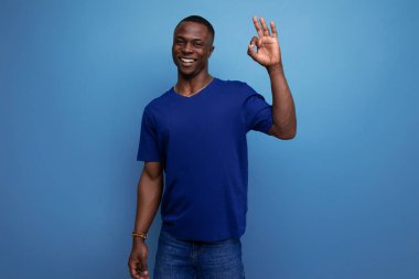 Çekici 25 'li yaşlarda sıradan mavi tişörtlü Afrikalı bir adam parmağını gösteriyor..